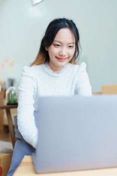 Starting small business entrepreneur of independent Asian woman smiling using computer laptop with cheerful success of online marketing package box items and SME delivery concept.