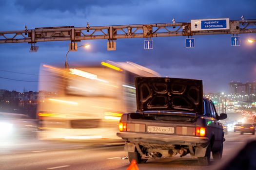 29.11.2022, Cherepovets, Russia.A large automobile bridge on which cars drive at night. There is a broken car and an emergency sign on the bridge. A bridge with large columns and lighting.