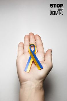 yellow blue ribbon in womans hand with words stop war in ukraine. concept needs help and support, truth will win