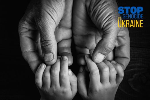 male hands hold childrens on a dark background with words stop genocide in ukraine black and white color and close up. concept needs help and support, truth will win