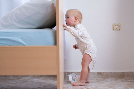 Caucasian baby girl playing hide and seek with her parents hiding above the bed