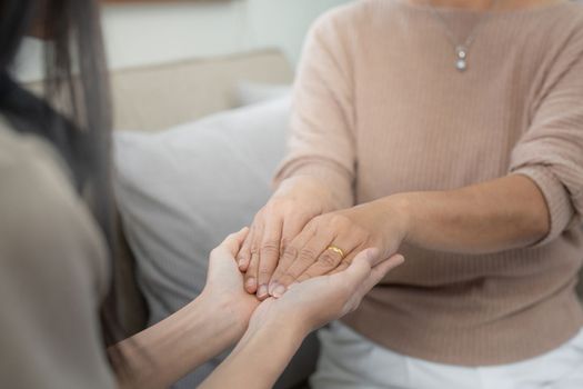 Loving adult daughter hugging older mother on couch at home, family enjoying tender moment together, young woman and mature mum or grandmother looking at each other, two generations.