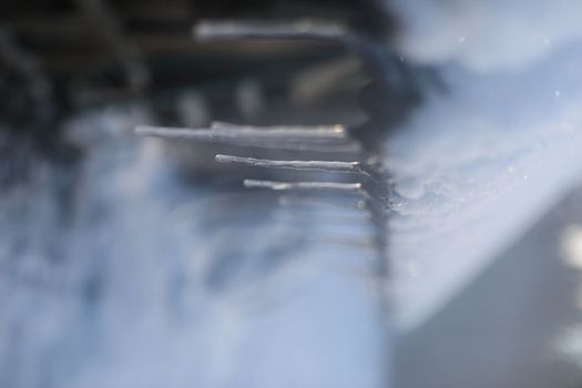 Spring background with icicles melting in the sun. Icicles close-up. Snow melting. The beginning of the warm season, the end of winter. Rustic scene in early spring.