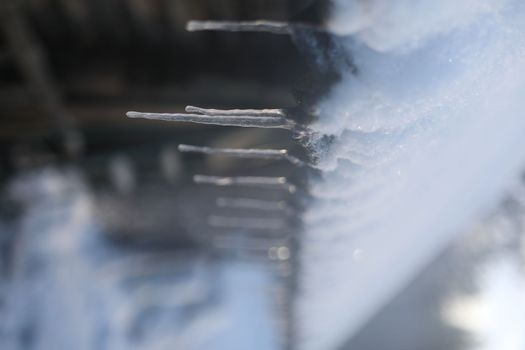 Spring background with icicles melting in the sun. Icicles close-up. Snow melting. The beginning of the warm season, the end of winter. Rustic scene in early spring.
