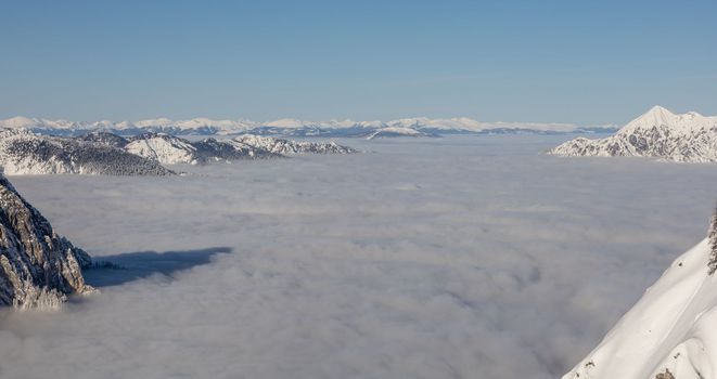 Winter mountains covered with snow landscape over clouds. High quality photo