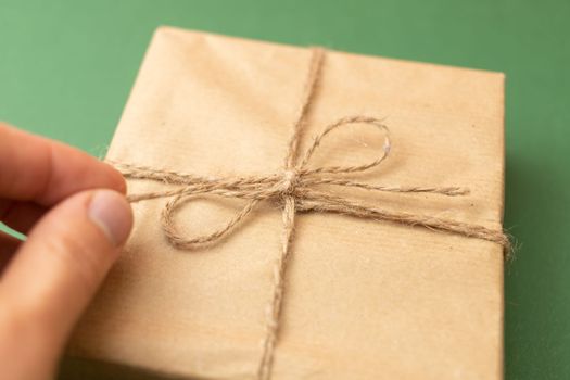 hand opening craft wrapped gift over green background. High quality photo