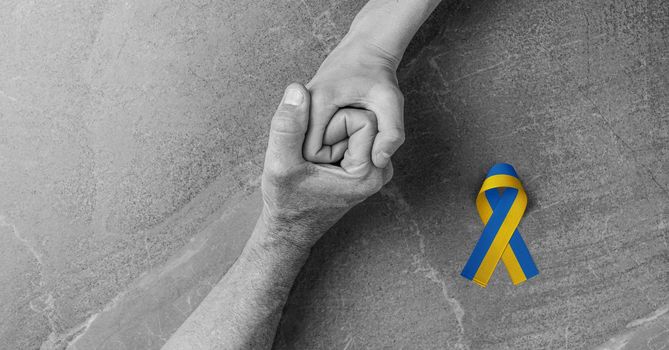 adult hand holding tight hand of child with yellow and blue ribbon black and white color. concept needs help and support, truth will win