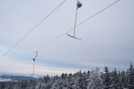 part of a ski lift against the backdrop of a magnificent winter landscape on the Wasserkuppe mountain in Rhen, Hesse, Germany. magical tall and large pines and snowy firs covered with snow and ice. The horizon creates an illusion and merges with the cloudy sky and fog, which covers all the space visible in the distance. High quality photo