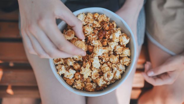 Friends eating popcorn on the street. Close-up of hands