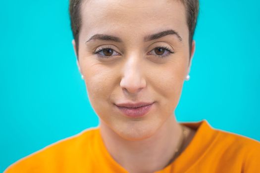 portrait of an attractive young caucasian girl with short hair looking at camera smiling isolated on blue background. High quality photo