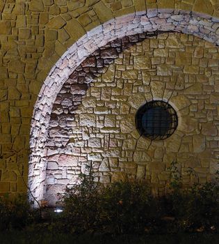 Round window with stone wall arch. Evening lighting. High quality photo