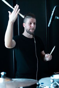 Caucasian drummer recording a drum part in a recording studio.