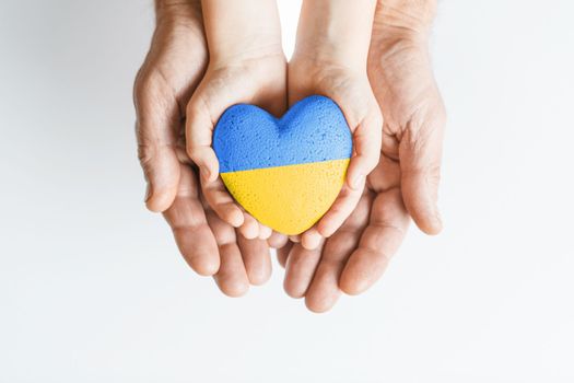 male hands hold childrens with painted yellow and blue heart on white background. concept needs help and support, truth will win