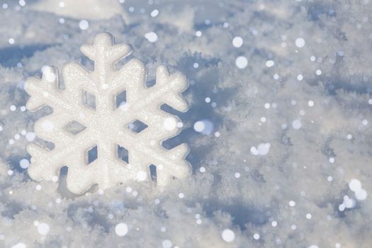 A snowflake in the snow. Festive background for the design. Christmas background with decorative snowflake on snow. Christmas decoration on natural snow.