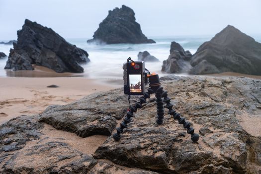 Digital mirrorless photo camera on flexible tripod to making photo of sea landscape. Photocamera on articulated tripod