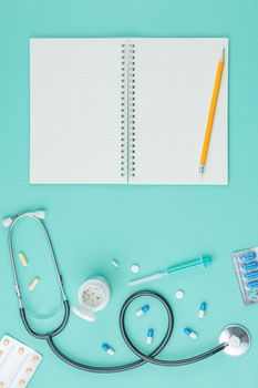 Nurse desktop concept. Medical equipment stethoscope and spiral notebook in doctor office on green desk background top view.