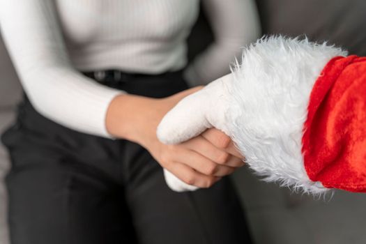 Santa shakes hands with a girl congratulating her on Christmas. New Year's greetings. Christmas holiday greeting. A gesture from Santa. Close-up