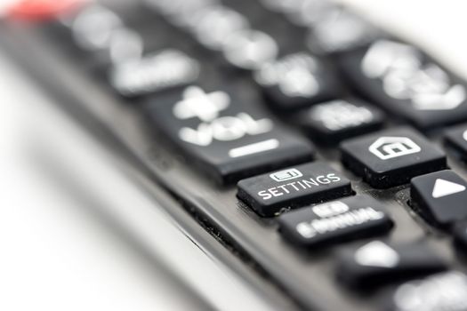 Close-up of a TV remote control isolated on white background with focus on the settings button, concept of smart TV