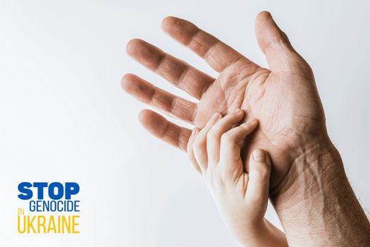 male hand hold children on white background with words stop genocide in ukraine. concept needs help and support, truth will win