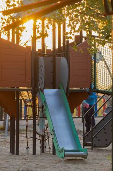 Playground at sunset with family and kids playing in the background.