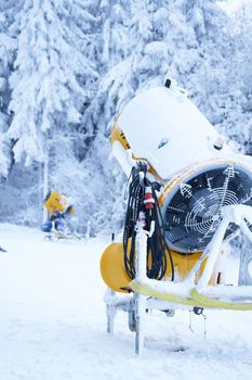 Yellow artificial snow cannon under snow on Wasserkuppe in Rhoen Hesse Germany ski resort on snowy mountain after fresh snow fall. High quality photo