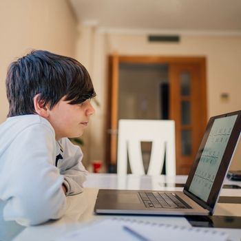 Serious school boy concentrated while studying maths at home. Home schooling and distance learning concept