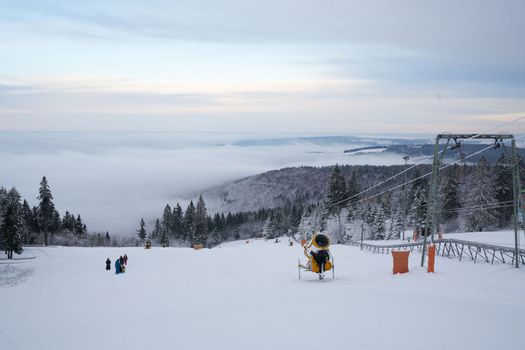 magnificent winter landscape on Wasserkuppe mountain in Ren, Hesse, Germany. magical tall and large pines and snowy firs covered with snow and ice. The horizon creates an illusion and merges with the cloudy sky and fog, which covers all the space visible in the distance. High quality photo