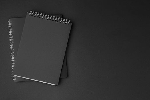 Black notebook with white spiral on dark isolated background. White and black concept flat lay.