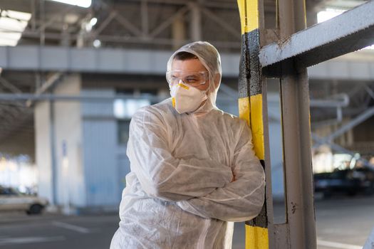 COVID-19 coronavirus doctor standing hospital parking dressed white protective overalls hazmat suit. Infectious disease pandemic medical worker front line, outbreak. Male medical worker medium shoot