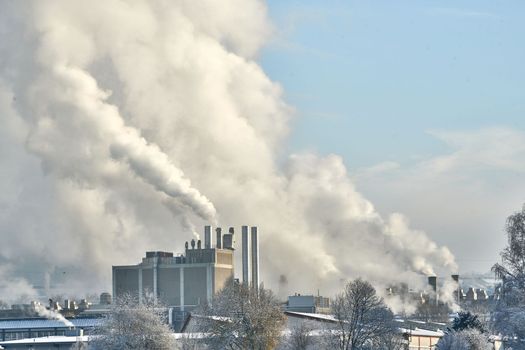 Environmental problem of pollution of environment and air in cities. Smoking industrial zone factory chimneys. View of large plant with Smoking pipes Smoke from the paper industry, which is running every day of the year. Photo taken December 2022 Air pollution in the city. Smoke from the chimney on blue sky background. High quality photo