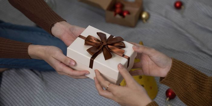 Happy woman giving Christmas and New Year Gift box to woman at Home.Family Xmas celebration. Christmas decoration. Relationship..