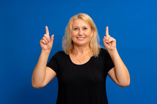 Closeup photo of excited energetic woman promoter pointing index fingers up suggest selected ads, casual wear isolated over blue color background