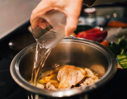 Woman hand adding water on a cooking pot. Preparing chicken soup. food cook chef concept