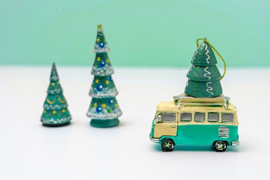 a toy car is carrying a toy Christmas tree. A Christmas tree and a minibus. Christmas and New Year. new year mood. Delivery. Copy space