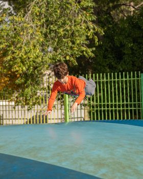 Kid playing and having fun while jumping on large inflatable bouncing trampoline upside down.