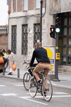 People driving a bicycle in Madrid city center road. Sustainability and ecology concepts.