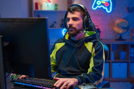 Male gamer focusing on online video games championship, playing action game on online live stream. Caucasian player having fun with virtual esport gameplay tournament on computer. High quality photo