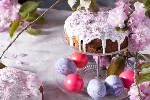 beautiful Easter cake on the table, and colored eggs, homemade cakes, still life with a silver teapot on a background of pink sakura. High quality photo