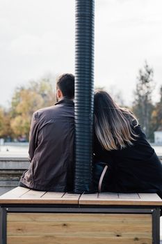 Loving couple sitting in front of lake view. Rear view. Man and woman traveling together. Traveler couple enjoying nature, embracing, watching landscape together. Copy space