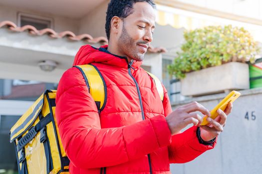 Courier man with yellow backpack searching address with mobile phone. Delivery food concept. Small business and delivery service concept. High quality 4k footage