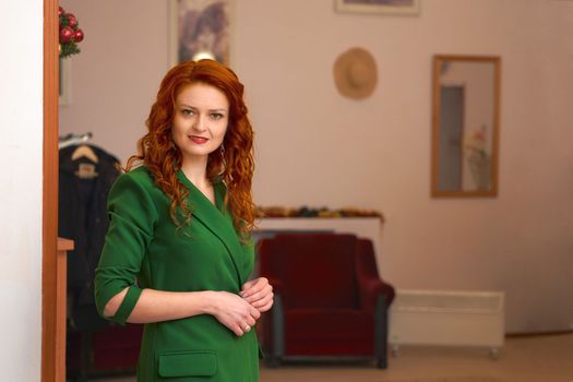 a room providing a space out of which one or more other rooms or corridors lead.Young red haired smiling woman in a green in the lobby of the hotel restaurant.