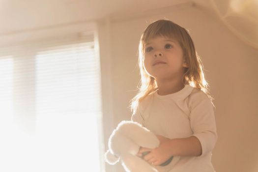 charming blonde baby with a toy in the morning.