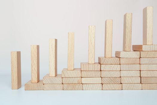 Domino effect climbing the stairs on a wooden staircase lined with steps. Business management ideas for sustainable growth and profitability.
