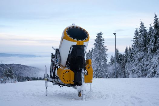 Yellow artificial snow cannon on Wasserkuppe ski resort in Rhoen Hesse Germany, on snowy mountain after fresh snow fall in 2022 december. High quality photo