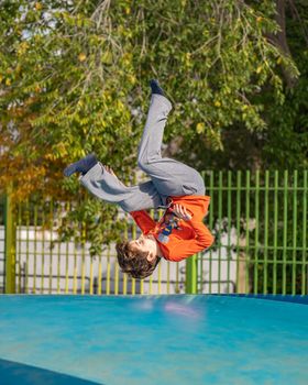 healthy sport little caucasian boy jumping somersault outdoors nature with copyspace.