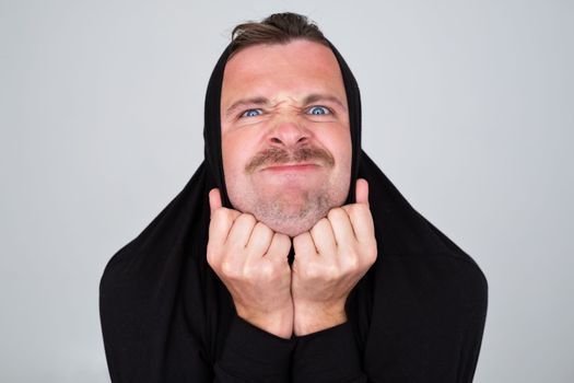 man hiding pulling sweater on head in displeasure, kfeeling nervous