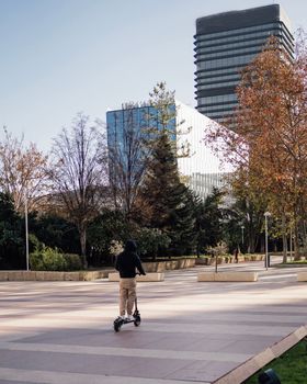 Madrid city downtown business area with a guy riding a electric scooter.