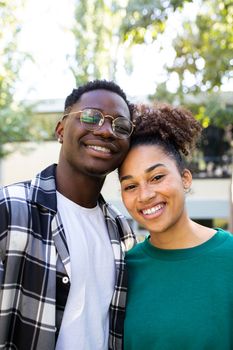 Vertical portrait of happy African American young couple outdoors looking at camera. Relationship concept.
