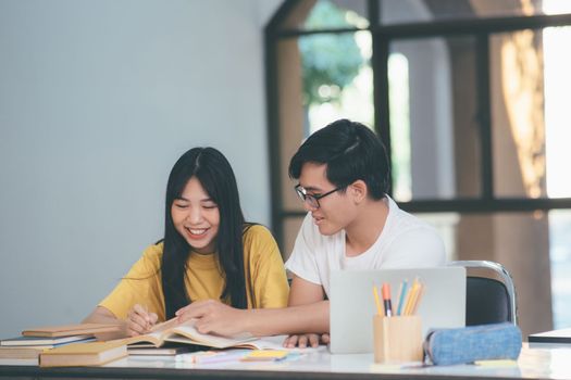 Young woman and man studying for a test or an exam. Tutor book with friends. Young students campus or classmates helps friend catching up workbook and learning tutoring in classroom, teaching, learning