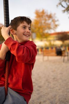 Young boy playing and having fun doing activities outdoors. Happiness and happy childhood concept. Child swing on rope.